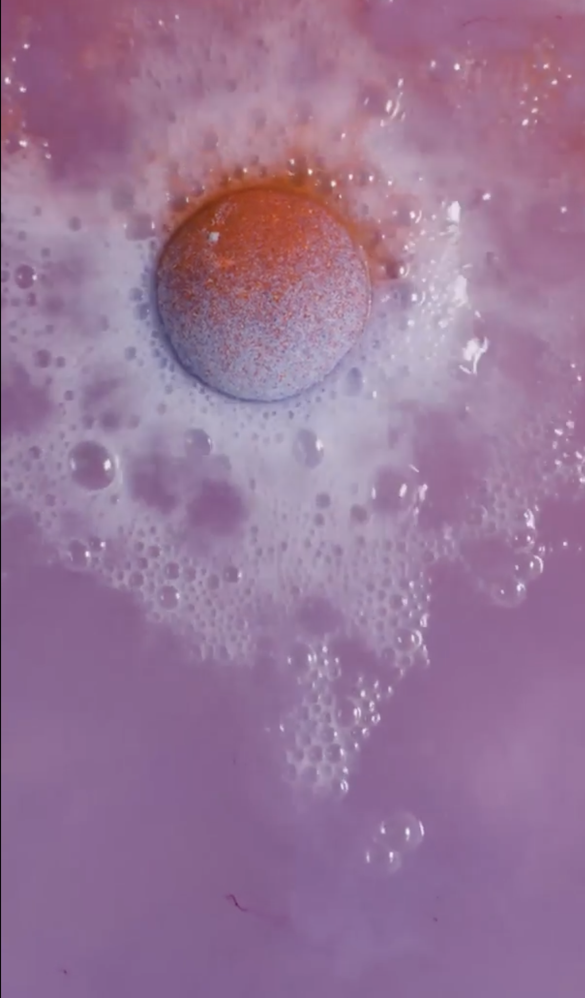 The Space Girl bath bomb is dissolving in the watering giving off energetic, foaming bubbles of deep purples with stunning flecks of red.