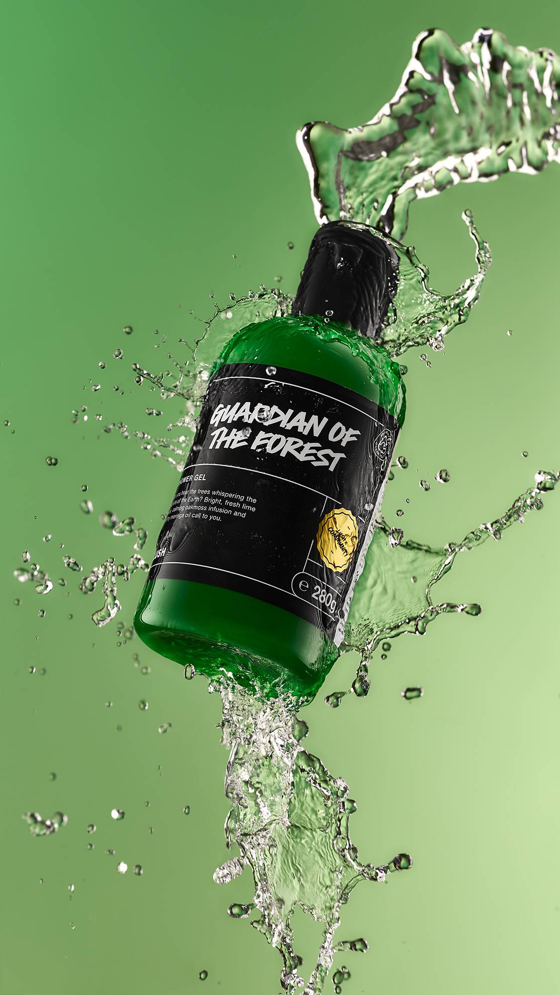 A high-definition action shot of the Guardian Of The Forest shower gel bottle mid-air being splashed by fresh water surrounded by droplets on a forest-green background.