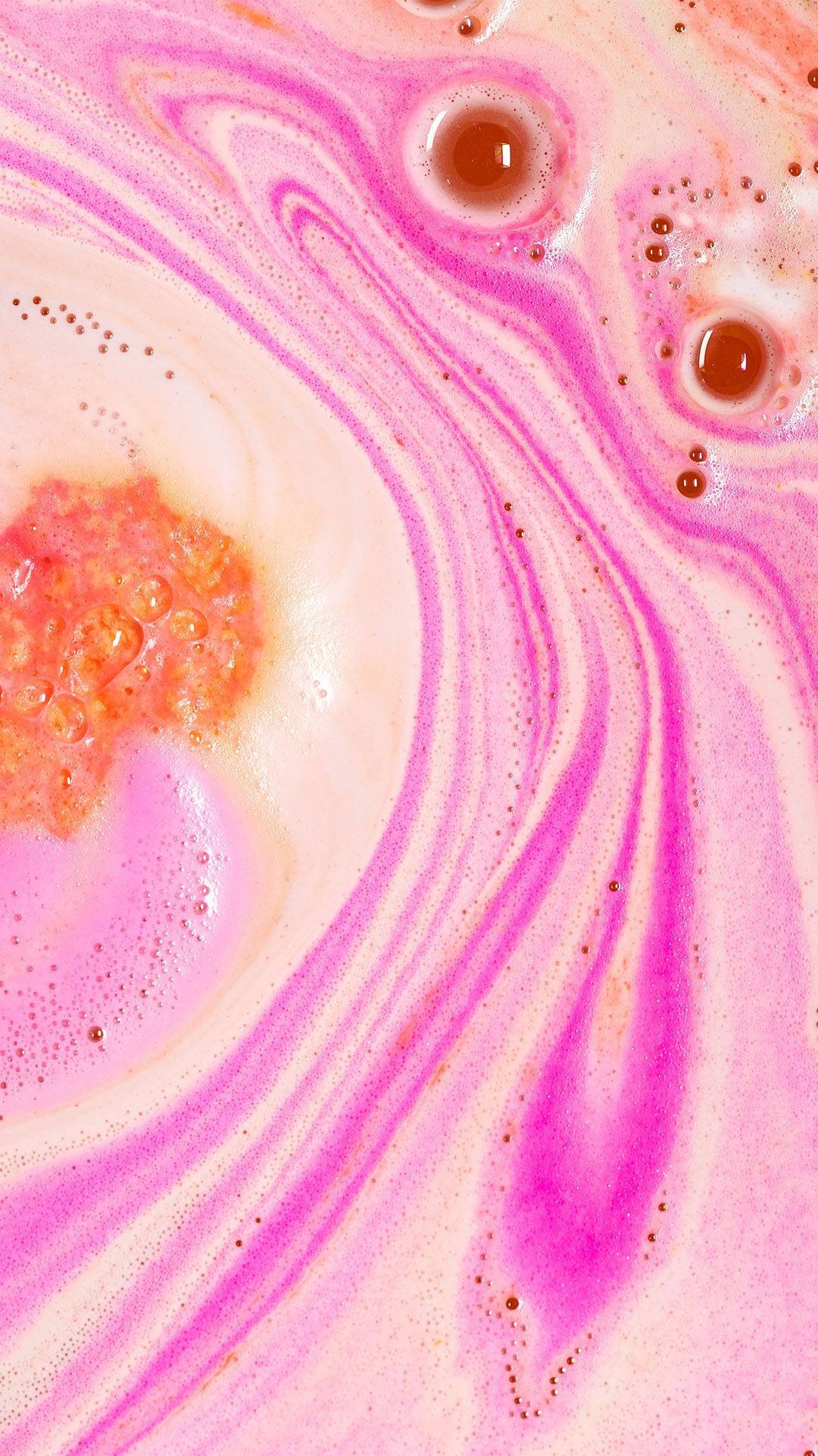 The Peachy bath bomb has almost fully dissolved leaving behind thick, colourful ripples of pink and peach-coloured, velvety foam. 